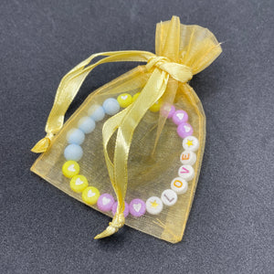 bracelet love pour les enfants en perles acryliques colorés. le bracelet est livré dans une joli pochon en tulle transparent 